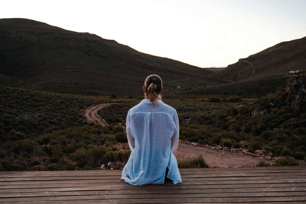 Woman contemplates a vast landscape from a deck.