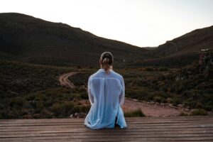 Woman contemplates a vast landscape from a deck.